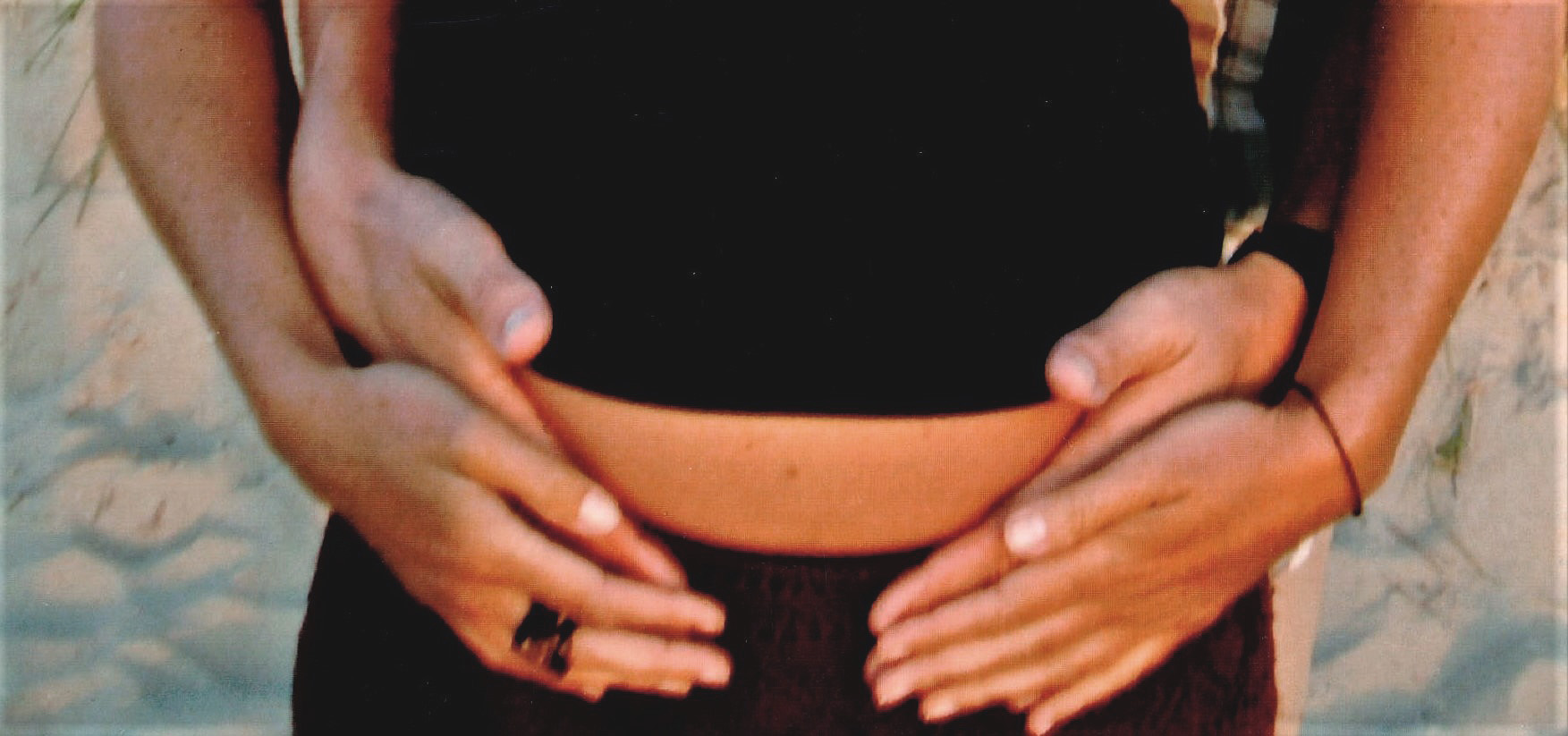 Schwangere und Partner umfassen Bauch mit Händen